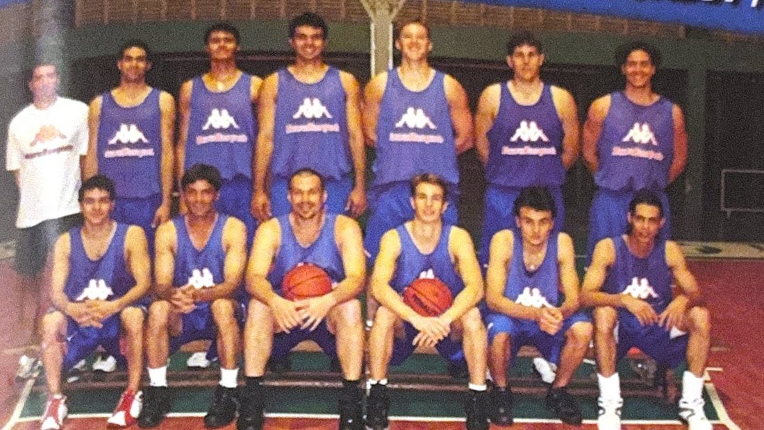 Time de basquete de camisa roxa, em duas fileiras, posando em quadra