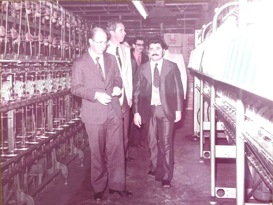 Visita dentro da fábrica têxtil, com máquinas em linha